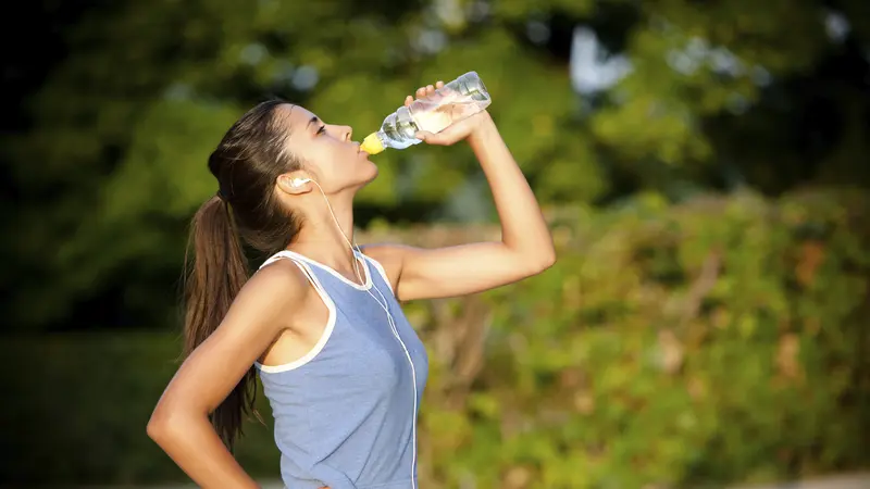 Pelari segar minum air kelapa setelah latihan lari untuk hidrasi dan elektrolit